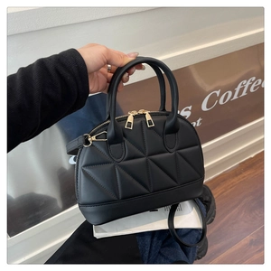 Dettaglio dell'elegante borsa a mano trapuntata nera con cerniere dorate e tracolla