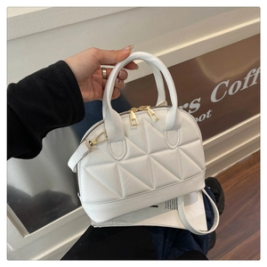 Dettaglio borsa a conchiglia bianca con trapuntatura geometrica e metallo dorato
