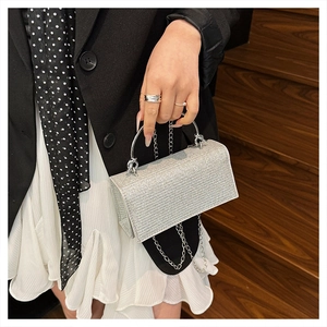 Detail of silver rhinestone evening clutch with curved metal handle and chain strap