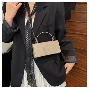 Detail view of champagne gold glitter clutch bag with metal handle and chain strap