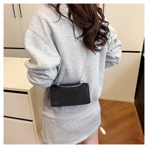 Detail showing the black sparkly evening clutch with silver chain strap on a model