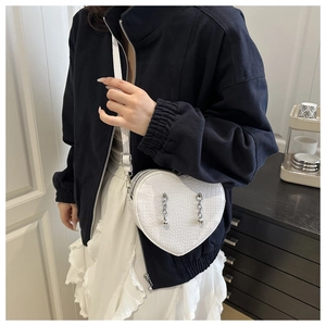 Detail of white heart-shaped crossbody bag with crocodile texture and beaded chain strap