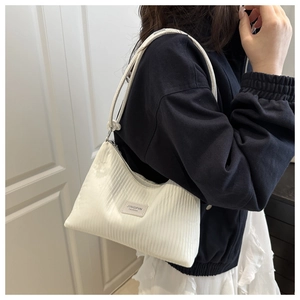 Detailed close-up of white corduroy shoulder bag with vertical pleats and fashion label