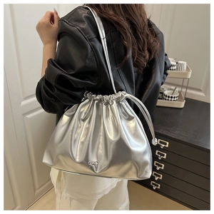 Detail of silver metallic drawstring bag with bow hardware shown on model shoulder