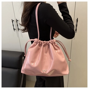 Detail of pink drawstring shoulder bag with glossy finish and silver bow ornament