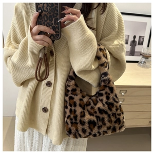 Detail einer trendigen Handtasche aus Kunstpelz mit Leopardenmuster und Strickpullover