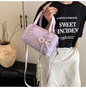 Detail of light purple Boston bag with snake skin texture and pearl bow charm
