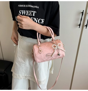 Detail of pink faux snakeskin boston bag with pearl bow charm and metal heart pendant