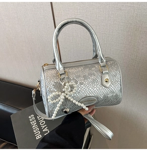Detail of silver boston bag with snake embossed texture and pearl butterfly charm