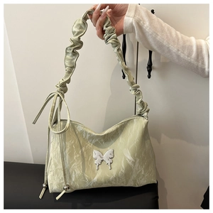Détail du sac cabas vert sauge avec texture plissée et breloque papillon argentée