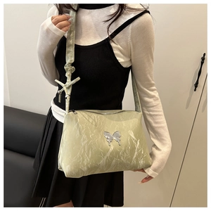 Détail du sac cabas vert clair froissé avec un ornement de papillon en métal argent