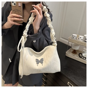 Détail du sac cabas blanc cassé avec breloque papillon argentée et bandoulière
