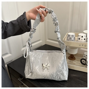 Détail du sac argenté métallisé avec texture plissée et boucle papillon en métal argenté