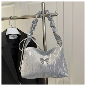 Détail du sac à main plissé argenté avec texture métallisée et boucle papillon
