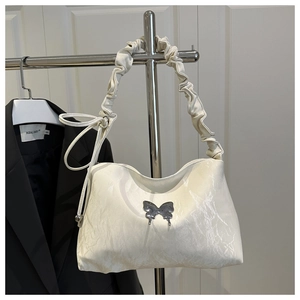 Détail du sac à bandoulière plissé blanc crème avec ornement papillon en métal argenté