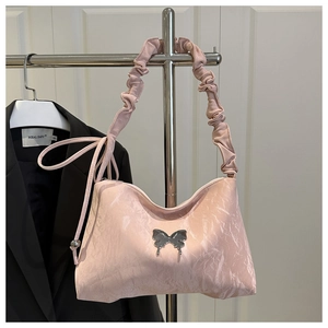 Détail du sac à bandoulière rose avec texture marbrée et ornement papillon argenté