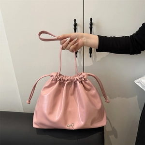 Pink soft leather drawstring bucket bag with metallic bow detail and long handles
