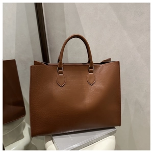 Detailed macro view of the brown crocodile texture and silver metal buckles on the tote bag