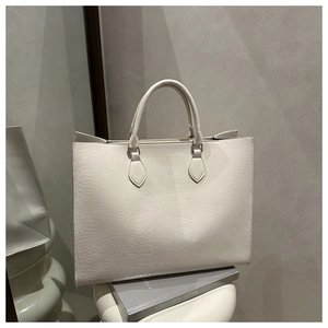 Detail showing the elegant crocodile pattern texture on a cream white tote bag