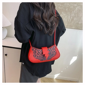 Détail du sac bandoulière léopard rouge avec boucle éclair porté par un mannequin