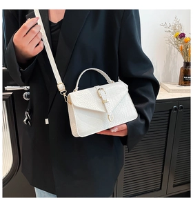 Détail macro de la texture cuir croco blanc avec boucle dorée élégante sur le sac à main