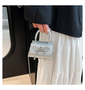 Detail of silver sequined mini handbag with large rhinestone bow and metal chain strap