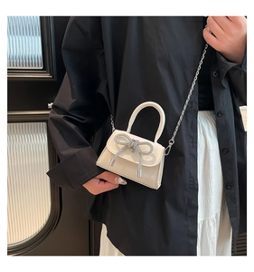 Détail d'un mini sac blanc cassé avec un nœud en strass argentés et bandoulière chaîne