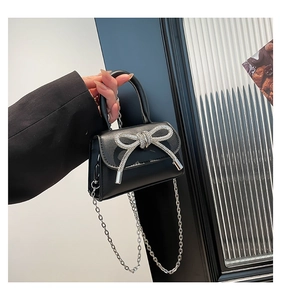 Close-up of a mini black handbag featuring a sparkling silver rhinestone bow detail