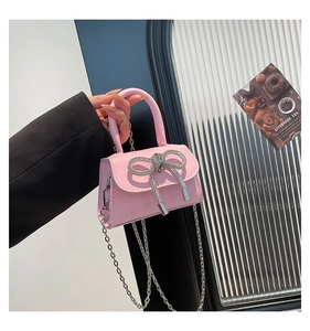 Detail of pink PU leather mini bag with sparkling rhinestone bow and silver chain strap