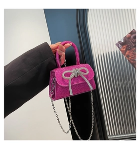 Macro shot of fuchsia sequin mini bag with rhinestone bow and silver chain strap