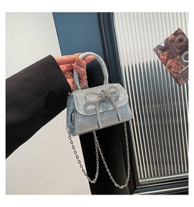 Detail of silver sequin mini handbag with crystal bow and metallic chain strap