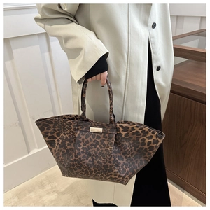Detail of leopard print tote bag featuring a gold logo plaque and textured faux leather