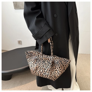 Detailed view of leopard print tote bag with gold metal trim and minimalist handle