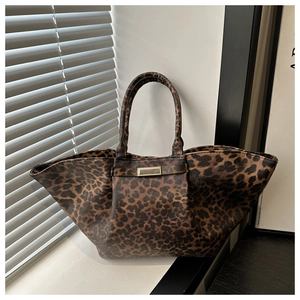 Close-up of leopard print tote bag with trapezoid wings and gold metal hardware