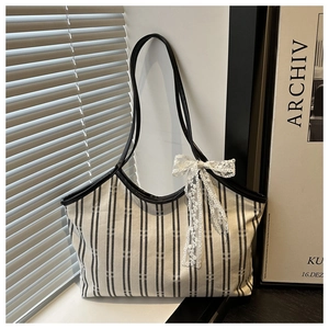 Detailed close-up of striped canvas tote bag with white lace bow on indoor window sill