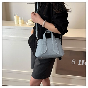 Close-up of light blue striped tote bag with detachable shoulder strap and metal studs