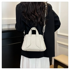 Detail of white textured tote bag with silver metal feet on a minimalist design