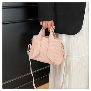 Detail showing the light pink tote bag's twill texture and gold metal protective feet