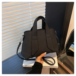 Detail of black striped tote bag with textured finish and silver metal hardware accents