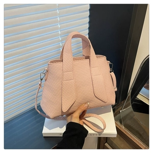 Detail of light pink tote bag featuring a diagonal woven texture and metal hardware
