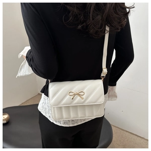 Back view of a model wearing a white quilted crossbody bag with a gold bow detail