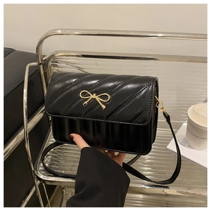 Vue détaillée du sac en cuir matelassé noir avec fermoir nœud doré et coutures en V