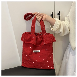 Macro detail of red floral tote bag featuring ruffle edges and AGOGO ORIGINAL woven label