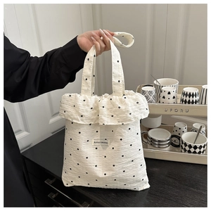 Detail of white ruffle tote bag with black floral print and pleated texture fabric