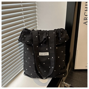Dettaglio di volant su borsa tote in mesh nera a fiori con etichetta AGOGO ORIGINAL