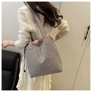 Detail showing side view of the gray drawstring tote bag with pink lining on the shoulder