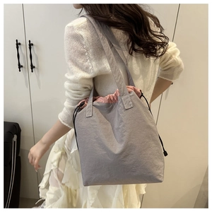 Detail of grey drawstring tote bag with pink lining and durable nylon webbing handles