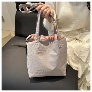 Detail of the grey nylon tote bag with pink drawstring closure and double handles