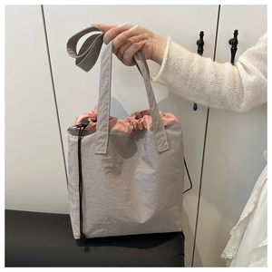 Close-up of light grey tote bag showing pink drawstring closure and adjustable strap