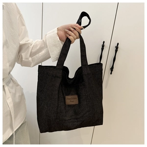 Gros plan du sac cabas en denim noir avec étiquette en cuir marron et texte Fashion Bag